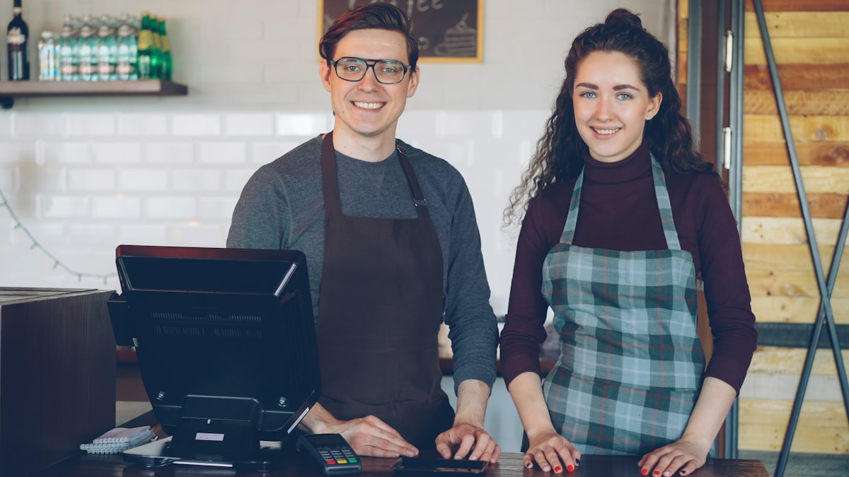 Dos empleados sonrientes atendiendo tras el mostrador de una cafetería